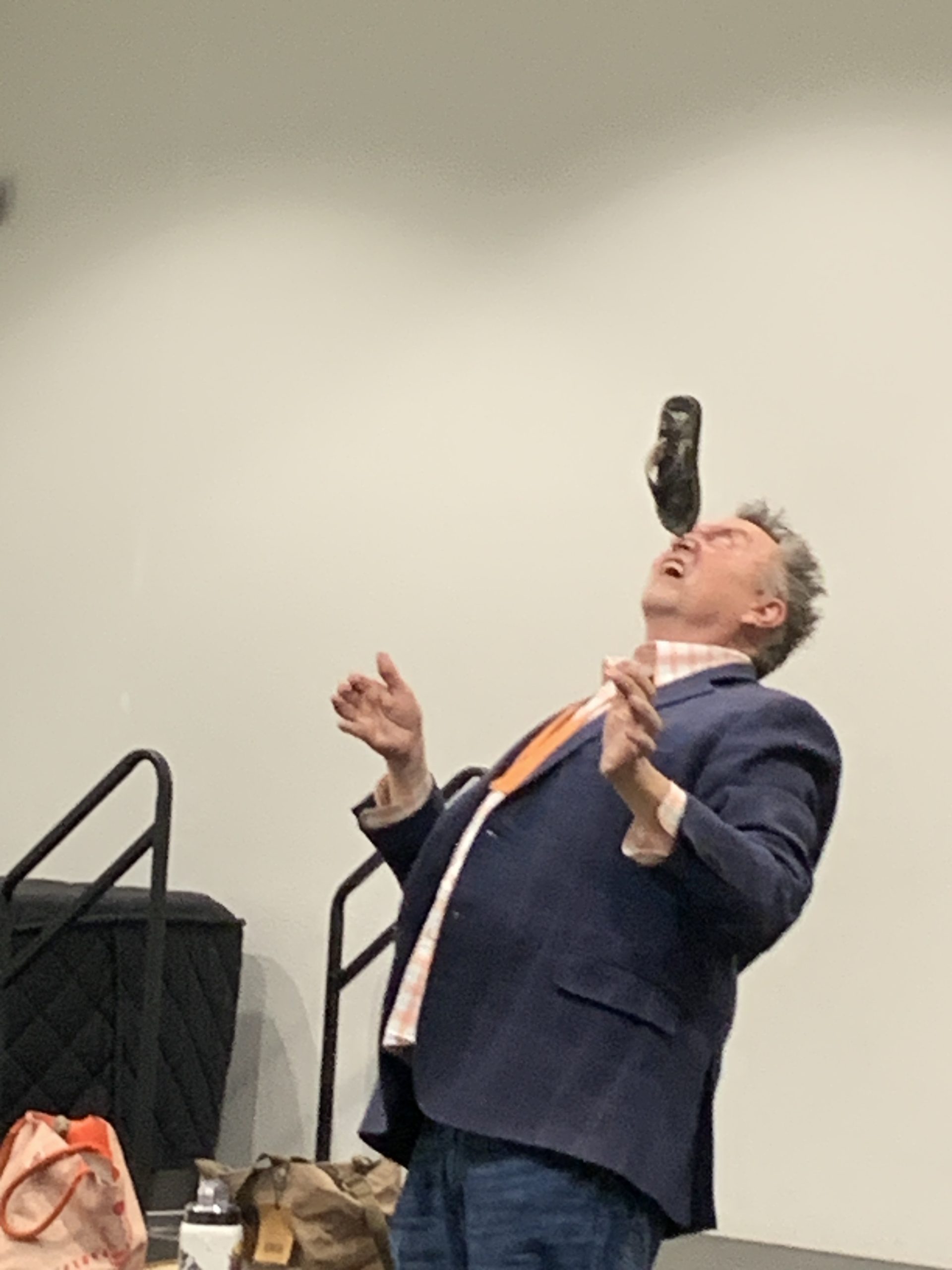 Comedic juggler balances a child's shoe on his nose during dia de los ninos