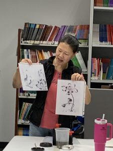 Completed black ink paintings shown by the instructor