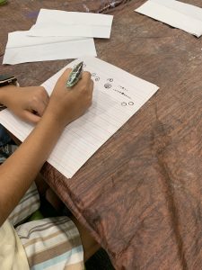 A participant practices drawing henna designs on paper